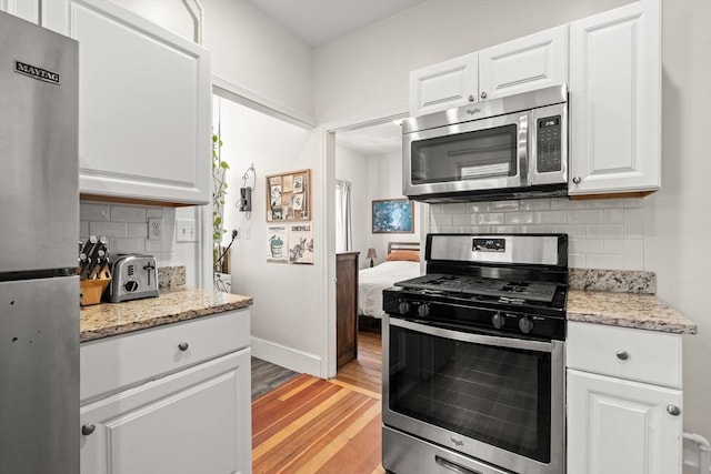 95 Child St Unit 2, Boston, MA 02130 - kitchen with appliances with stainless steel finishes, light wood-style flooring, tasteful backsplash, and white cabinets