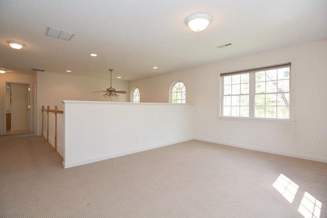 spare room featuring light colored carpet, a ceiling fan, baseboards, and visible vents
