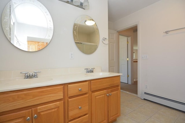 bathroom featuring tile patterned flooring, a sink, baseboard heating, and double vanity