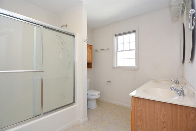 bathroom featuring double vanity, tile patterned flooring, baseboards, toilet, and a shower with door