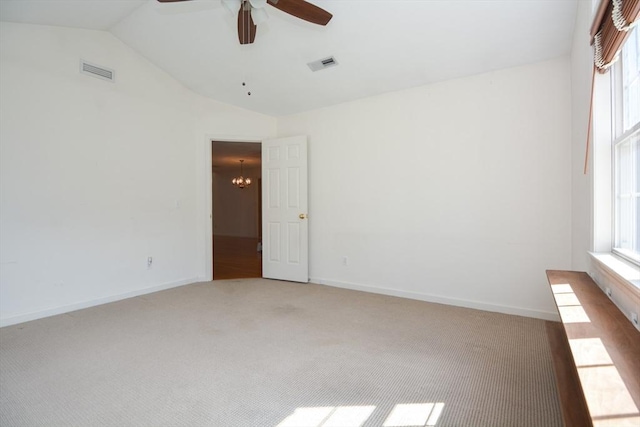 spare room with a healthy amount of sunlight, light colored carpet, lofted ceiling, and visible vents