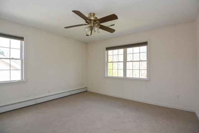 spare room with ceiling fan, visible vents, baseboard heating, baseboards, and light carpet