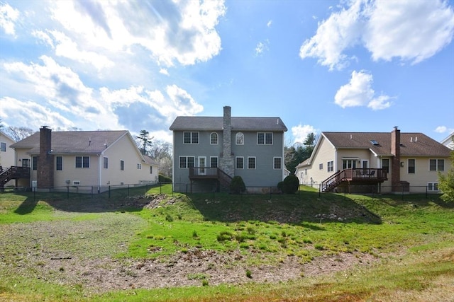 back of property with stairway, a deck, a fenced backyard, and a lawn