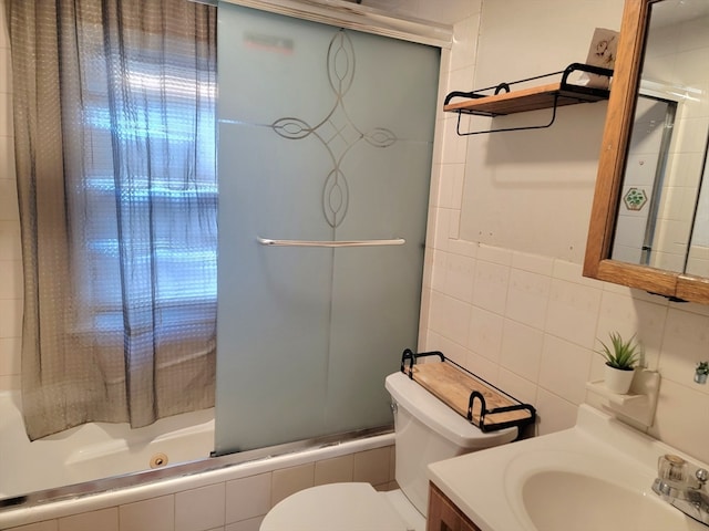 full bathroom featuring toilet, vanity, tile walls, and combined bath / shower with glass door