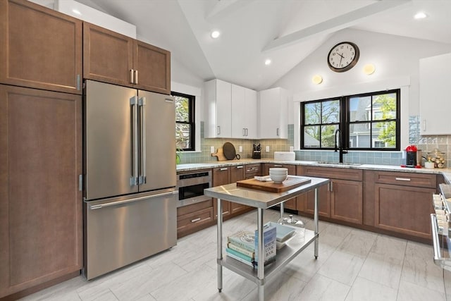 9 Upland Rd, Marblehead, MA 01945 - kitchen featuring appliances with stainless steel finishes, a sink, tasteful backsplash, white cabinetry, and plenty of natural light