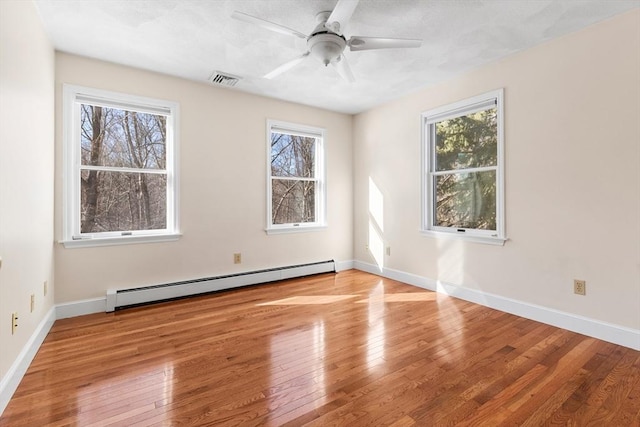 spare room featuring a baseboard radiator, ceiling fan, and light wood-type flooring