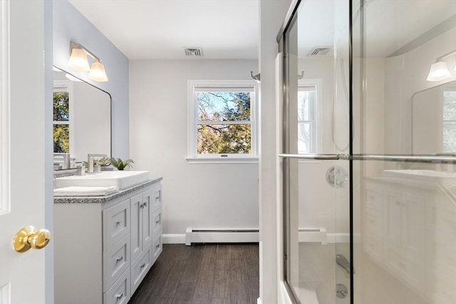 bathroom featuring a shower with door, vanity, wood-type flooring, and a baseboard heating unit