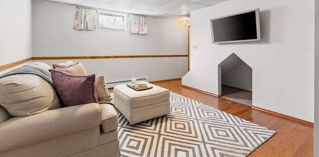 living room featuring baseboard heating, a paneled ceiling, and wood-type flooring