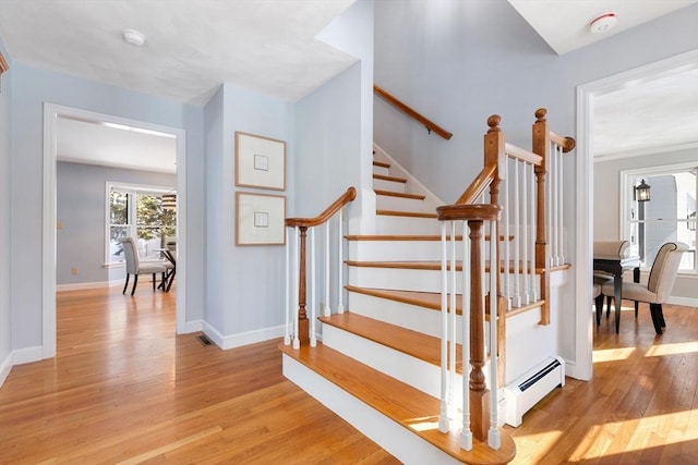 stairway with hardwood / wood-style floors and baseboard heating