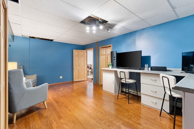 office area featuring a drop ceiling, built in desk, light hardwood / wood-style floors, and a baseboard radiator