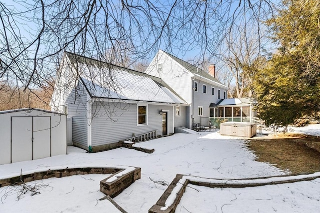 snow covered house with a hot tub and a storage unit