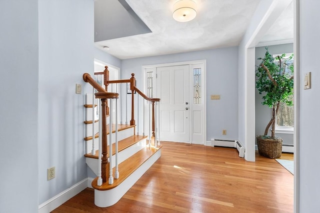 foyer entrance with a baseboard heating unit and light wood-type flooring