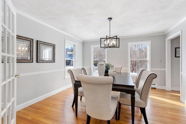 dining area with ornamental molding, a baseboard heating unit, a chandelier, and light wood-type flooring