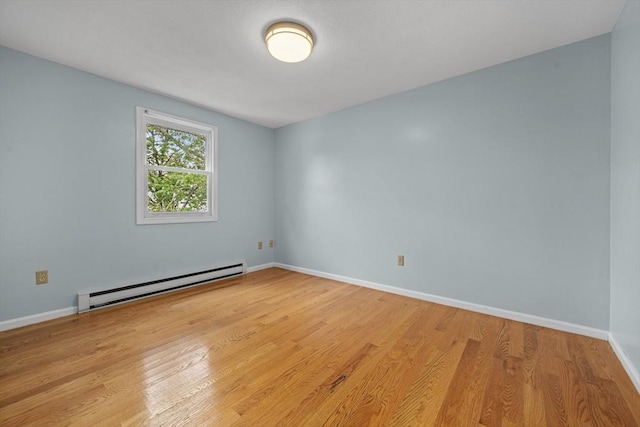 spare room featuring a baseboard radiator, wood finished floors, and baseboards