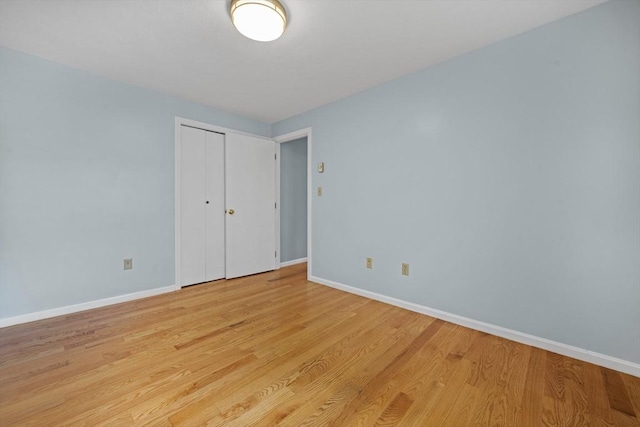 unfurnished bedroom featuring baseboards, light wood-style flooring, and a closet