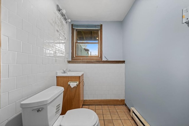 half bathroom featuring tile walls, toilet, tile patterned flooring, vanity, and baseboard heating