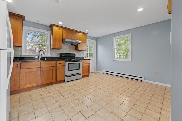 kitchen with stainless steel range with electric cooktop, a baseboard heating unit, freestanding refrigerator, backsplash, and brown cabinets
