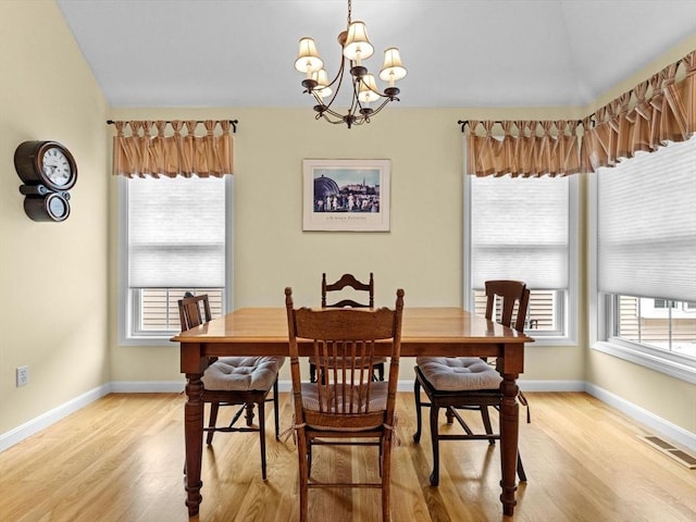 dining space with light wood-type flooring, a chandelier, and plenty of natural light