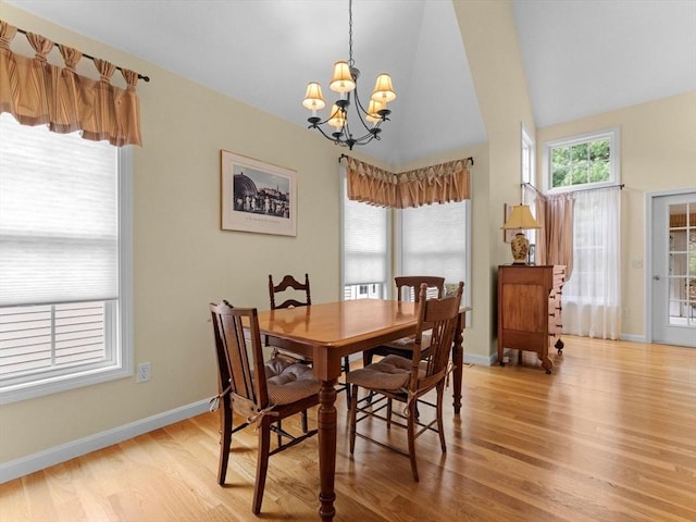 dining space featuring light wood-style flooring, a chandelier, baseboards, and high vaulted ceiling