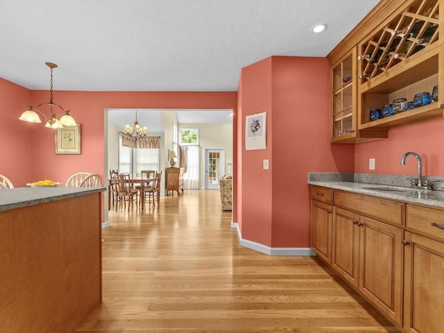 kitchen featuring light wood-style floors, a sink, a chandelier, brown cabinetry, and recessed lighting