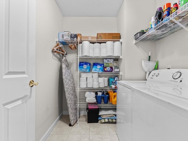 clothes washing area featuring washer and clothes dryer, baseboards, and tile patterned floors