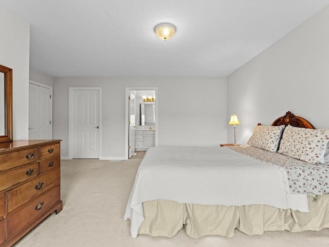 bedroom with light carpet, baseboards, and ensuite bathroom