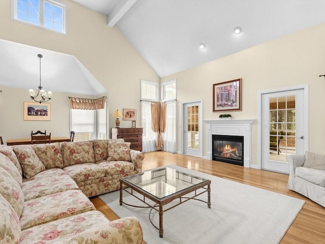 living room with a chandelier, wood finished floors, high vaulted ceiling, beamed ceiling, and healthy amount of natural light