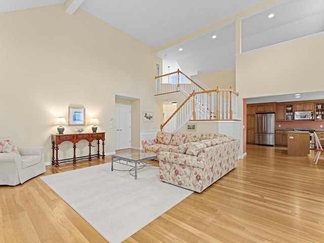 living room with high vaulted ceiling, stairway, light wood-style floors, recessed lighting, and beam ceiling
