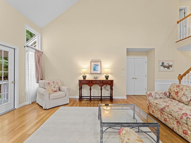 living area with high vaulted ceiling, wood finished floors, and baseboards