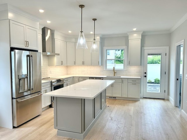 50 York Ave Unit 50, Watertown, MA 02472 - kitchen featuring appliances with stainless steel finishes, wall chimney range hood, light countertops, light wood finished floors, and decorative backsplash