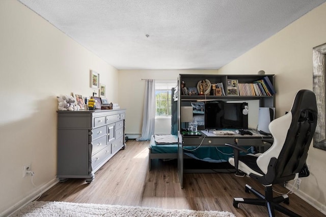 135 Grove St Unit 145, Rockland, MA 02370 - bedroom featuring wood finished floors, an office area, a baseboard heating unit, and a textured ceiling