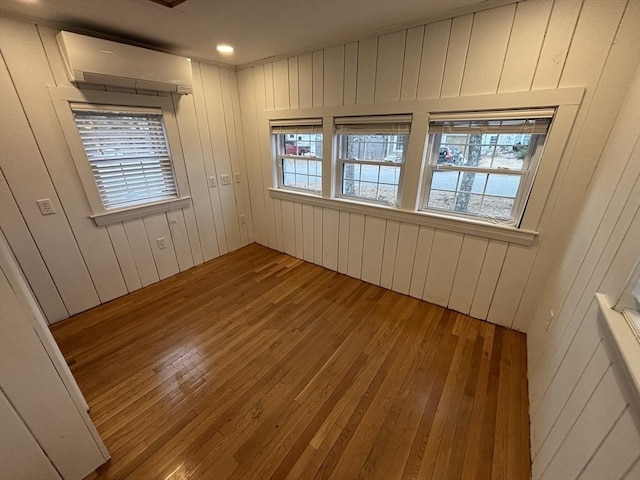 spare room featuring hardwood / wood-style floors and a wall unit AC