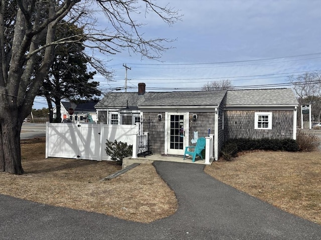 view of front of home with a shingled roof and fence