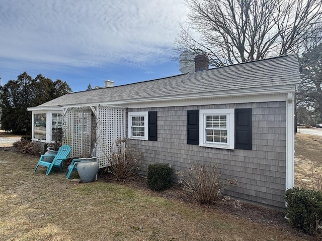 view of home's exterior featuring a chimney and roof with shingles