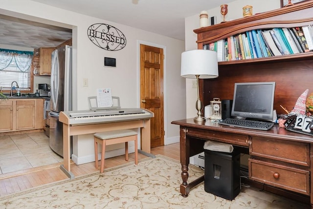 office with sink and light hardwood / wood-style flooring