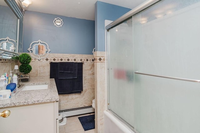 full bathroom featuring tile patterned floors, bath / shower combo with glass door, tile walls, baseboard heating, and vanity