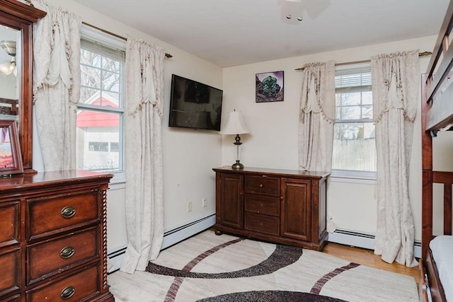 bedroom with multiple windows and a baseboard heating unit