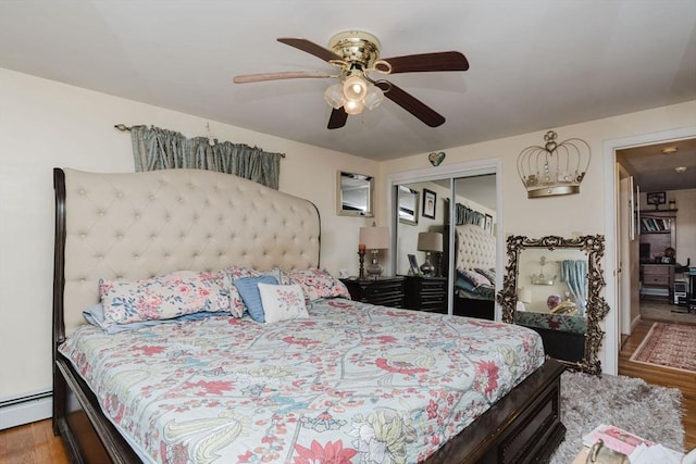 bedroom featuring wood-type flooring, ceiling fan, baseboard heating, and a closet