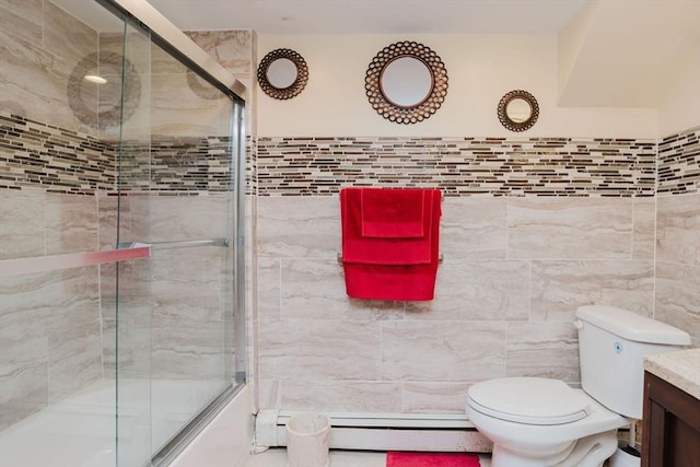 full bathroom featuring combined bath / shower with glass door, a baseboard radiator, tile walls, vanity, and toilet