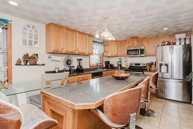 kitchen featuring decorative light fixtures, sink, a kitchen breakfast bar, light tile patterned floors, and stainless steel appliances