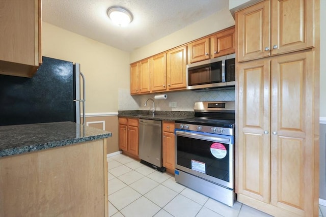 3 Dailey St Unit I, Attleboro, MA 02703 - kitchen featuring stainless steel appliances, backsplash, dark stone countertops, light tile patterned flooring, and a sink