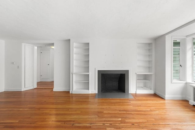 220 Prospect St, Seekonk, MA 02771 - unfurnished living room featuring built in shelves, a textured ceiling, hardwood / wood-style flooring, a fireplace with flush hearth, and baseboards