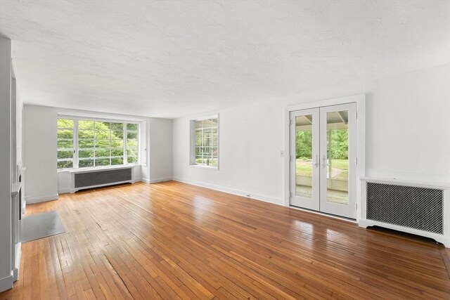 220 Prospect St, Seekonk, MA 02771 - unfurnished living room featuring radiator, hardwood / wood-style floors, french doors, and baseboards