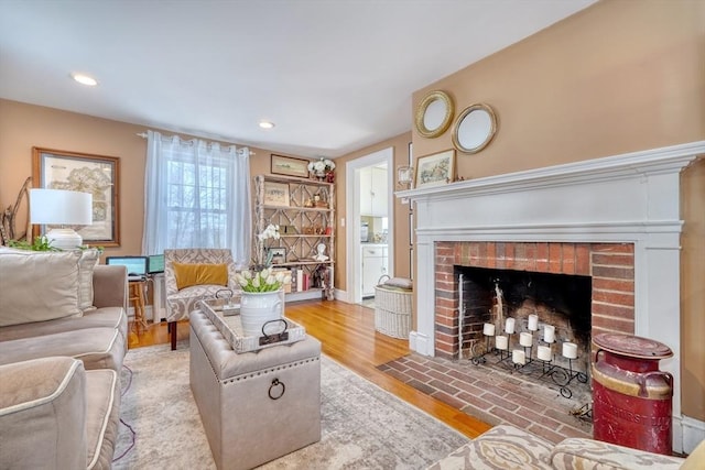 living room featuring a brick fireplace and light hardwood / wood-style flooring