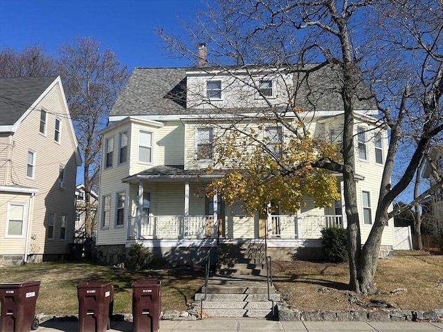 view of front of home with a chimney, covered porch, and a shingled roof