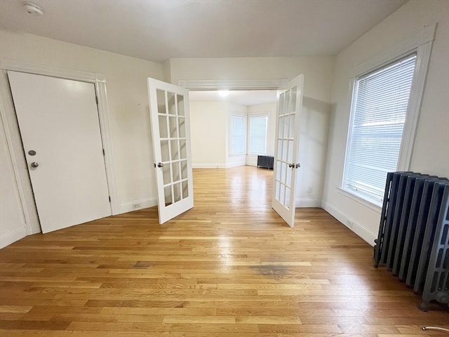 interior space with french doors, light wood-style flooring, and radiator heating unit