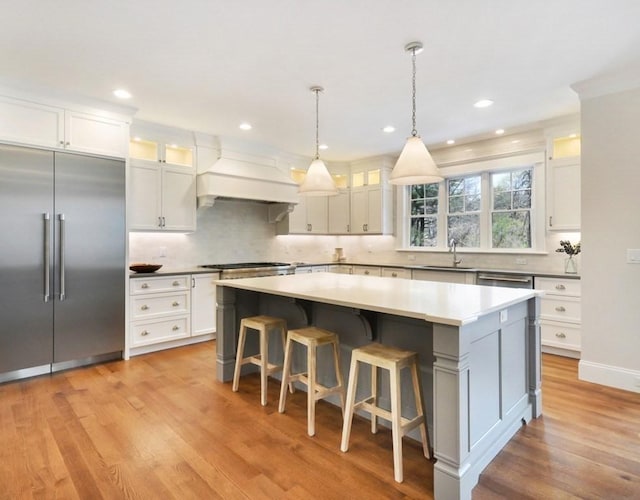 kitchen with a center island, white cabinets, custom range hood, and appliances with stainless steel finishes