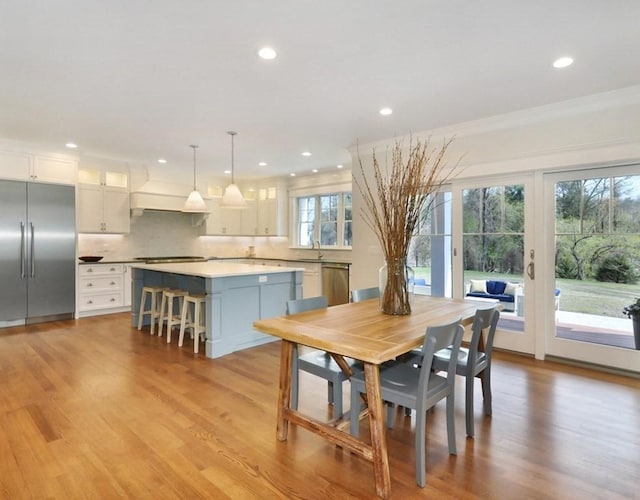 dining space with crown molding, sink, and light hardwood / wood-style floors