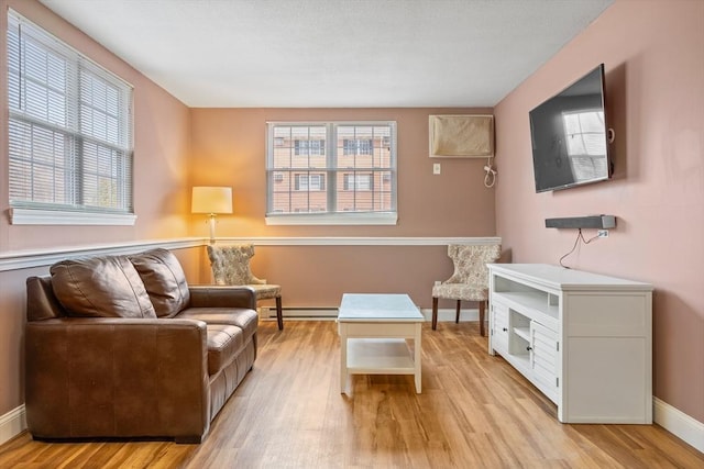 living area with light wood finished floors, a healthy amount of sunlight, and a baseboard radiator