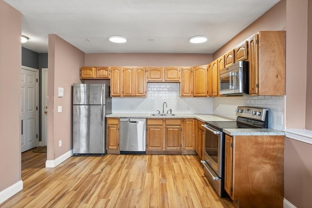 kitchen with decorative backsplash, appliances with stainless steel finishes, light countertops, and light wood-style floors